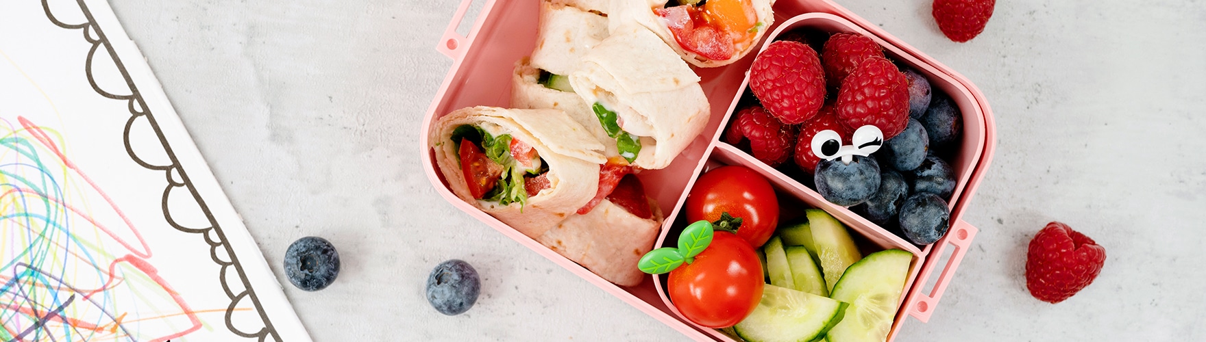 Kids’ lunch box with fruit, cucumber and a wrap with ERU Kids