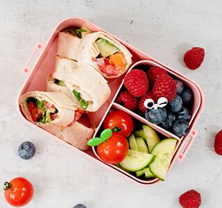 Kids’ lunch box with fruit, cucumber and a wrap with ERU Kids